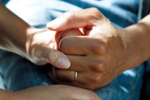 closeup of two people's clasped hands in a comforting hold