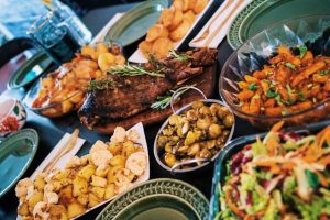 a feast with bowls of different kinds of food. potatoes, meat, mushrooms, salad, etc.